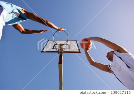 Men, player and basketball game at outdoor court or low angle of challenge team, dunk on rival. Male people, hoop or score point in summer park on fitness match or competition, athlete at blue sky 139017115