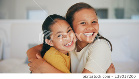 Siblings, portrait and sisters hug in home with love, care and kids with support on sofa in living room. Happy, face and children bonding in embrace together on couch in lounge of apartment or house 139017200