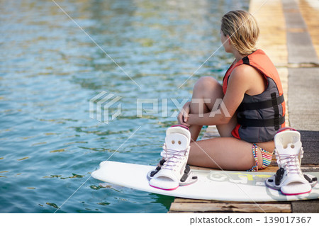 Woman, ready or wakeboard by water, lake or ocean sea with ideas, vision and planning fitness hobby. Person, life jacket and thinking athlete with swimsuit, exercise and training equipment for sports Woman, ready or wakeboard by water, lake or ocean sea with ideas, vision and planning fitness hobby. Person, life jacket and thinking athlete with swimsuit, exercise and training equipment for sports 139017367