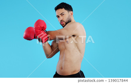 Fitness, boxer and portrait of man stretching in studio for workout, training or mindset on blue background. Health, exercise and face of male athlete with boxing gloves for body, warm up or sports Fitness, boxer and portrait of man stretching in studio for workout, training or mindset on blue background. Health, exercise and face of male athlete with boxing gloves for body, warm up or sports 139017844