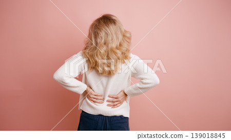 Woman experiencing lower back pain in studio Woman experiencing lower back pain in studio 139018845