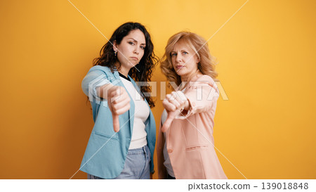 Two women showing disagreement with thumbs down gesture Two women showing disagreement with thumbs down gesture 139018848
