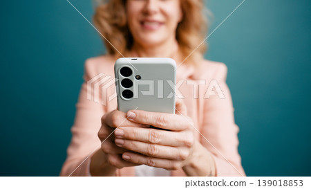 Woman holding mobile phone looking at digital content Woman holding mobile phone looking at digital content 139018853