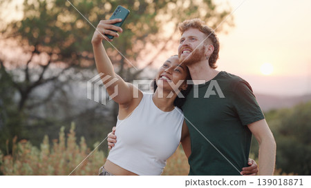 Happy couple taking selfie enjoying sunset outdoors 139018871