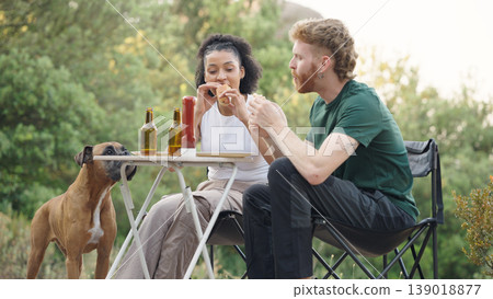 Couple eating hot dogs with dog at outdoor picnic 139018877