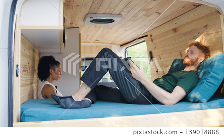 Couple relaxing inside a camper van enjoying van life Couple relaxing inside a camper van enjoying van life 139018888