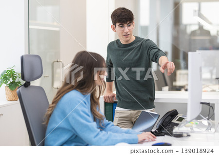 Colleagues collaborating on computer in modern office 139018924