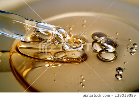 Pipette drawing golden liquid serum with bubbles Pipette drawing golden liquid serum with bubbles 139019089