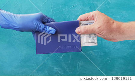 Airport check-in. Quarantine travel. Immigration officer in glove giving passenger passport boarding pass on blue background. Airport check-in. Quarantine travel. Immigration officer in glove giving passenger passport boarding pass on blue background. 139019151