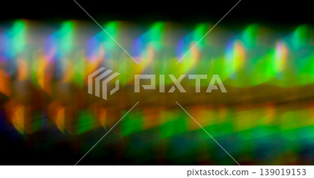 Rainbow defocused flare. Art lens texture. Blending green orange blue color light on black. Illuminated prism gradient abstract background. Rainbow defocused flare. Art lens texture. Blending green orange blue color light on black. Illuminated prism gradient abstract background. 139019153