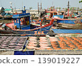 Fish are sun-dried on nets outdoors, with fishing boats anchored far away, at Ban Amphoe beach ,Thailand. 139019227
