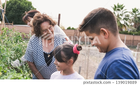 Happy senior woman looking at grandson in community garden Happy senior woman looking at grandson in community garden 139019889