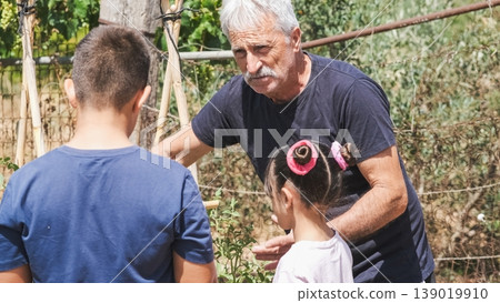 Elderly man explaining planting techniques to grandchildren at garden Elderly man explaining planting techniques to grandchildren at garden 139019910