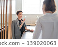 Two women discussing standing by table with wood slat divider in contemporary open office. Discussing, standing, divider, office, teamwork, women. 139020063