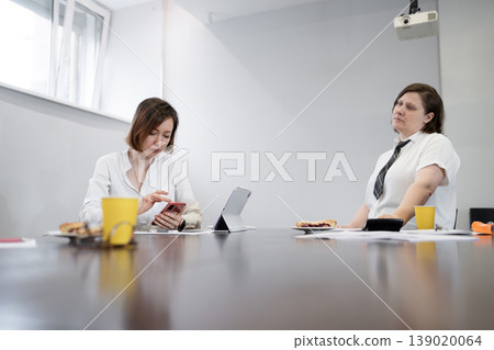 Businesswoman in white shirt reviewing documents with coffee and yellow cup in daylight office. Reviewing, documents, coffee, office, businesswoman. Businesswoman in white shirt reviewing documents with coffee and yellow cup in daylight office. Reviewing, documents, coffee, office, businesswoman. 139020064