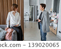 Female professionals greeting and meeting each other, standing near wood wall in modern office corridor. Greeting, office, businesswomen, standing, meeting. 139020065