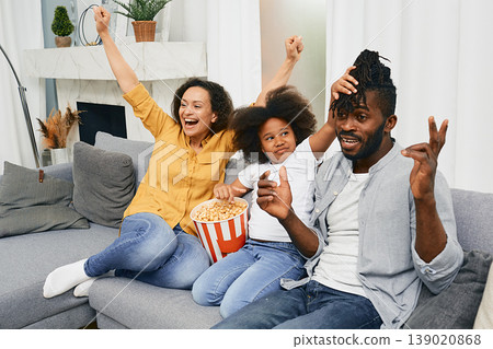 Positive family enjoys time together and watching a fun tv show with popcorn. Happy family togetherness 139020868