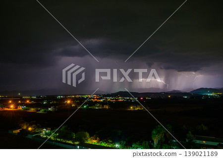 Majestic lightning display illuminates the dark night sky over a tranquil town 139021189