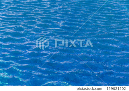 Rippling azure waters reflecting sunlight on a tranquil summer afternoon by the beach Rippling azure waters reflecting sunlight on a tranquil summer afternoon by the beach 139021202