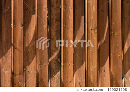 Shadows play across a wooden fence in the warm afternoon light of a serene backyard setting 139021208