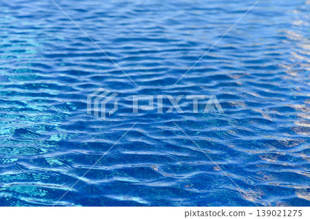 The tranquil beauty of shimmering water ripples under the sun on a serene day at the poolside oasis The tranquil beauty of shimmering water ripples under the sun on a serene day at the poolside oasis 139021275