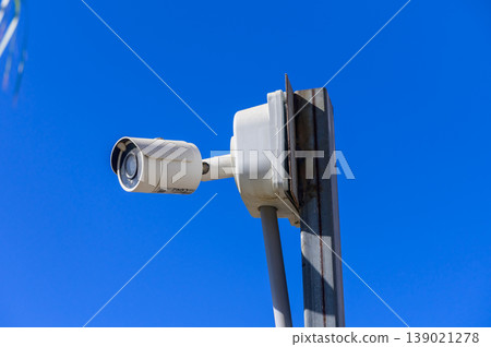 Surveillance camera mounted against clear blue sky in a modern urban setting Surveillance camera mounted against clear blue sky in a modern urban setting 139021278