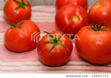 Freshly picked ripe tomatoes arranged on a striped cloth in a rustic kitchen setting Freshly picked ripe tomatoes arranged on a striped cloth in a rustic kitchen setting 139021314