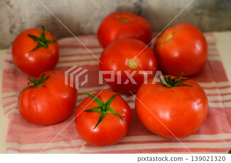 Freshly harvested red tomatoes arranged invitingly on a vintage kitchen towel for a rustic display 139021320