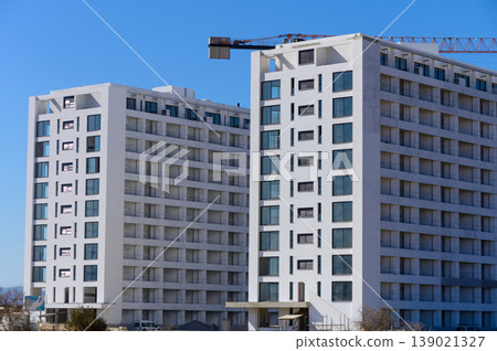Modern residential buildings under construction with a crane against a clear blue sky Modern residential buildings under construction with a crane against a clear blue sky 139021327