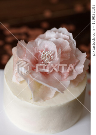Small white cake with pink flower on wooden table with confetti in minimal room Small white cake with pink flower on wooden table with confetti in minimal room 139022192