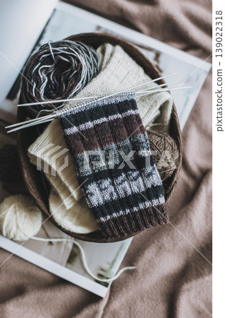 Hand knitted socks with needles and yarn ball in a basket. Concept for handmade and hygge slow life. Hand knitted socks with needles and yarn ball in a basket. Concept for handmade and hygge slow life. 139022318