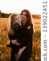 Mother Embraces Daughter. Gentle Silhouette Of Mother Shielding Daughter In Field Glow 139022451