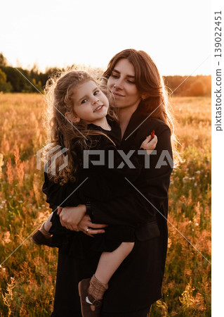 Mother Embraces Daughter. Gentle Silhouette Of Mother Shielding Daughter In Field Glow Mother Embraces Daughter. Gentle Silhouette Of Mother Shielding Daughter In Field Glow 139022451