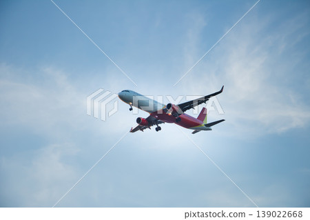 Modern passenger jet descending with landing gear extended in a soft evening sky. Clean composition with copy space, ideal for travel, aviation, and transportation concepts. Modern passenger jet descending with landing gear extended in a soft evening sky. Clean composition with copy space, ideal for travel, aviation, and transportation concepts. 139022668