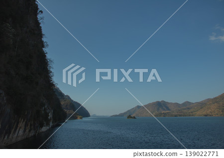 Wide mountain lake under clear blue sky with small island and calm water, peaceful nature landscape background with copy space. Wide mountain lake under clear blue sky with small island and calm water, peaceful nature landscape background with copy space. 139022771