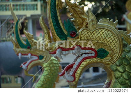 Golden Naga serpent statue detail at public Thai temple, mythological guardian sculpture and traditional Buddhist architecture. 139022974