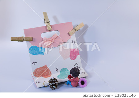 Cute decorative gift bag with colorful hand drawn hearts, small figurine and ornaments. Romantic love concept for Valentine's Day, relationship, greeting card or celebration background. 139023140