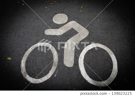 White bicycle lane symbol painted on asphalt road surface. Cycling path marking for urban transportation, eco-friendly travel and traffic safety concept. Top view with copy space. White bicycle lane symbol painted on asphalt road surface. Cycling path marking for urban transportation, eco-friendly travel and traffic safety concept. Top view with copy space. 139023225