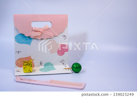 Decorative gift bag with heart pattern, small present, comb and ornament on white background. Minimal celebration and love concept with copy space. 139023249