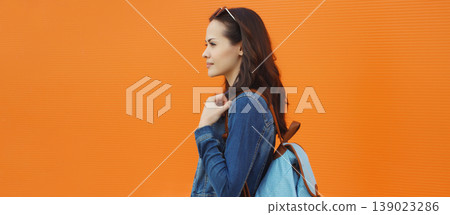 young woman student in casual with backpack against orange wall background young woman student in casual with backpack against orange wall background 139023286