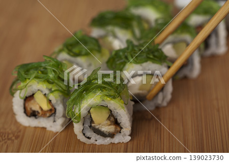 Hand Taking Sushi with Chopsticks. Japanese Cuisine Sushi Being Picked with Chopsticks. Hand Taking Sushi with Chopsticks. Japanese Cuisine Sushi Being Picked with Chopsticks. 139023730