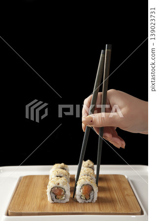 Hand Taking Sushi with Chopsticks. Japanese Cuisine Sushi Being Picked with Chopsticks. Hand Taking Sushi with Chopsticks. Japanese Cuisine Sushi Being Picked with Chopsticks. 139023731