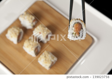 Hand Taking Sushi with Chopsticks. Japanese Cuisine Sushi Being Picked with Chopsticks. Hand Taking Sushi with Chopsticks. Japanese Cuisine Sushi Being Picked with Chopsticks. 139023738