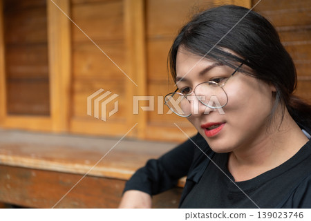 Close up of LGBTQ woman wearing glasses looking thoughtful indoors warm wooden background natural light lifestyle portrait calm confidence and authenticity Close up of LGBTQ woman wearing glasses looking thoughtful indoors warm wooden background natural light lifestyle portrait calm confidence and authenticity 139023746
