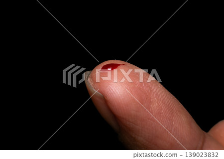 Close up of fingertip with small blood drop isolated on dark background medical concept injury wound health care and first aid detail Close up of fingertip with small blood drop isolated on dark background medical concept injury wound health care and first aid detail 139023832