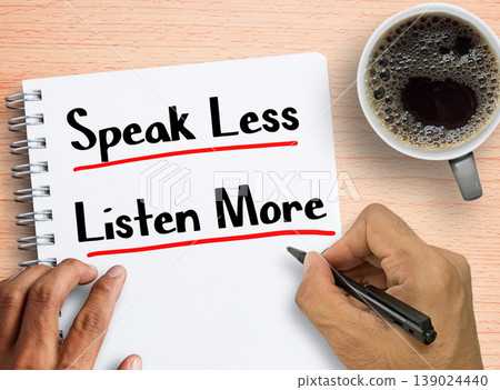 Man writing quote Speak less listen more on notebook with coffee on wood table background Man writing quote Speak less listen more on notebook with coffee on wood table background 139024440
