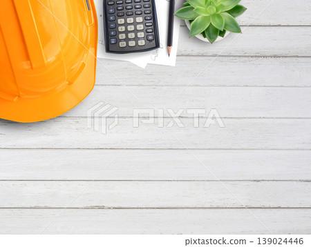 Orange safety helmet or hard hat,coffee,calculator and construction paper plans on wood table background. 139024446