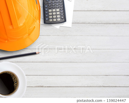 Orange safety helmet or hard hat,coffee,calculator and construction paper plans on wood table background. Orange safety helmet or hard hat,coffee,calculator and construction paper plans on wood table background. 139024447