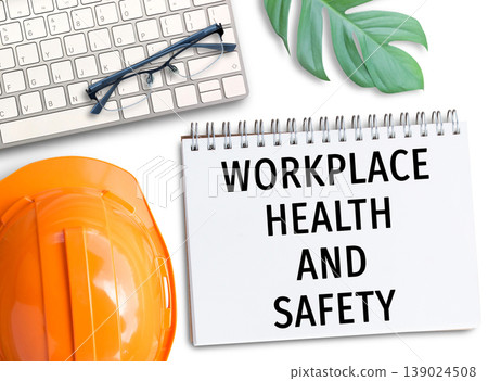 Orange safety helmet with words workplace health and safety write in notebook. Orange safety helmet with words workplace health and safety write in notebook. 139024508