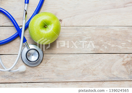 Top view green apple with blue stethoscope on wood table background. Top view green apple with blue stethoscope on wood table background. 139024565